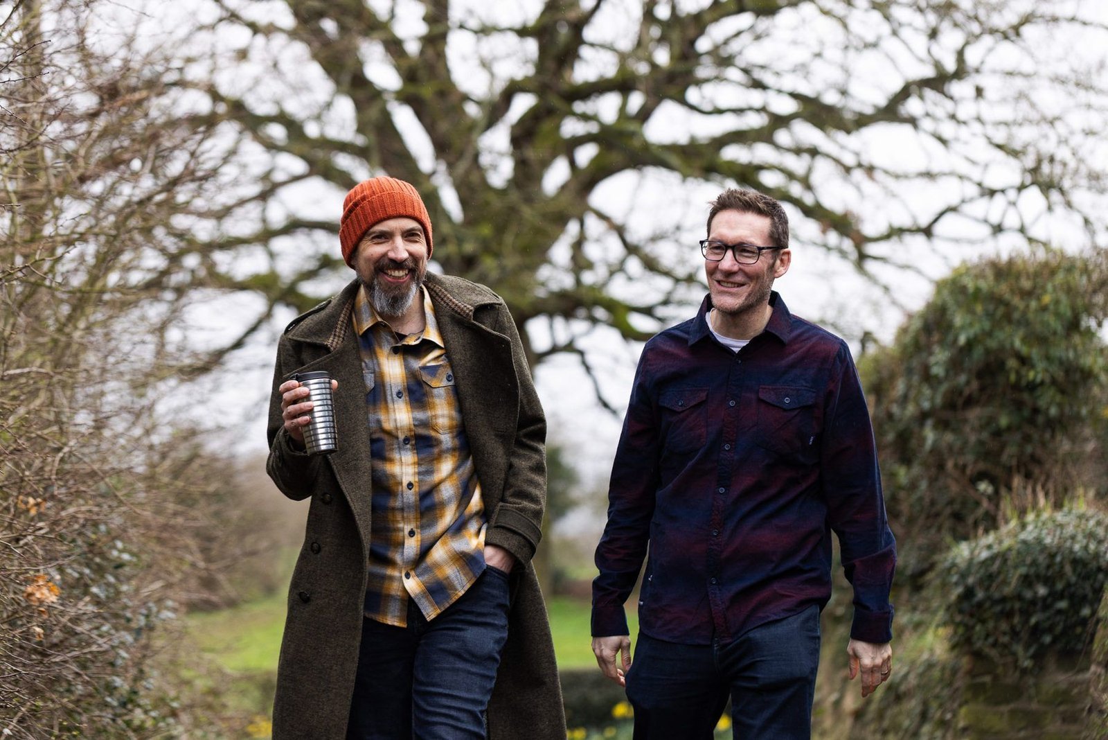 James and Garry laughing as they walk with coffee